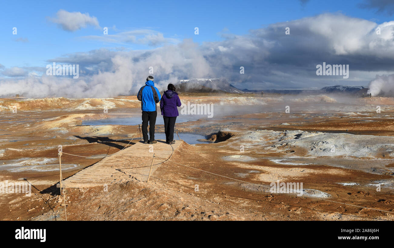 Ein paar Touristen beobachten Die Namafjall geothermale Region im Nordosten Island befindet sich auf der Ostseite des Sees Myvatn. Stockfoto