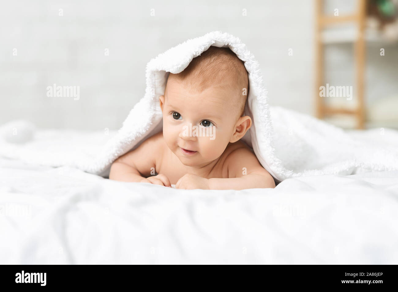Adorable neugeborenen Jungen liegend auf Bett unter weiche, weiße Decke Stockfoto