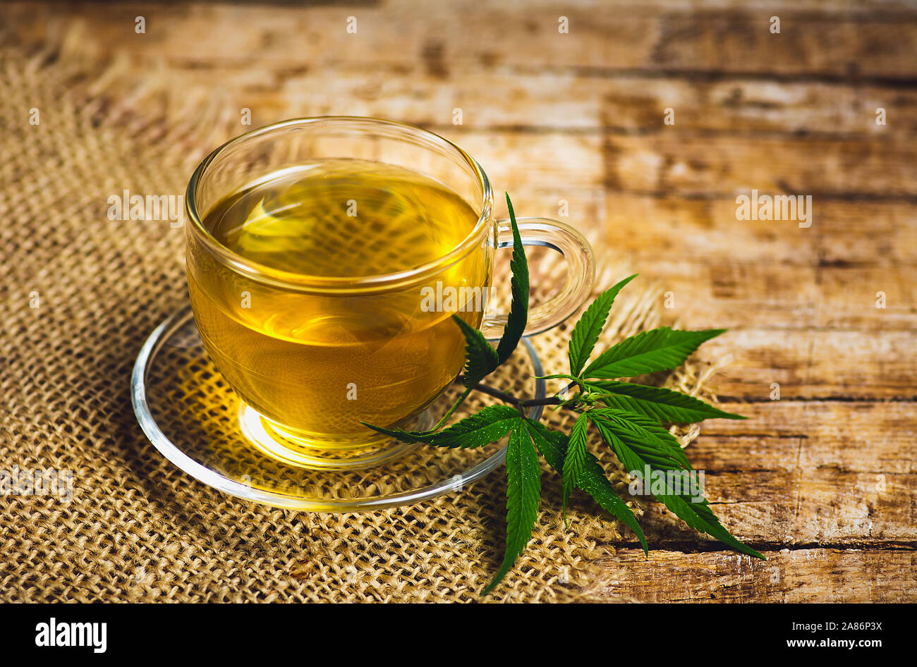 Marihuana Kräutertee in ein Glas und Cannabis Blätter Stockfoto