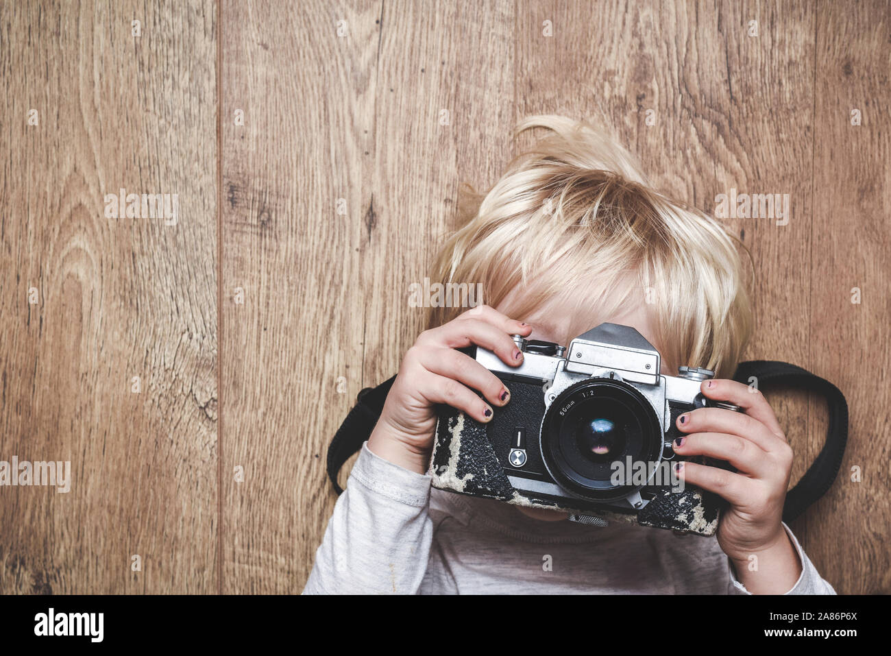 Junge, ein Foto mit einem Vintage Kamera zu Hause erlernen, wie Sie ein Bild das Kind hält die Kamera mit beiden Händen und nach Linse bei der v Stockfoto