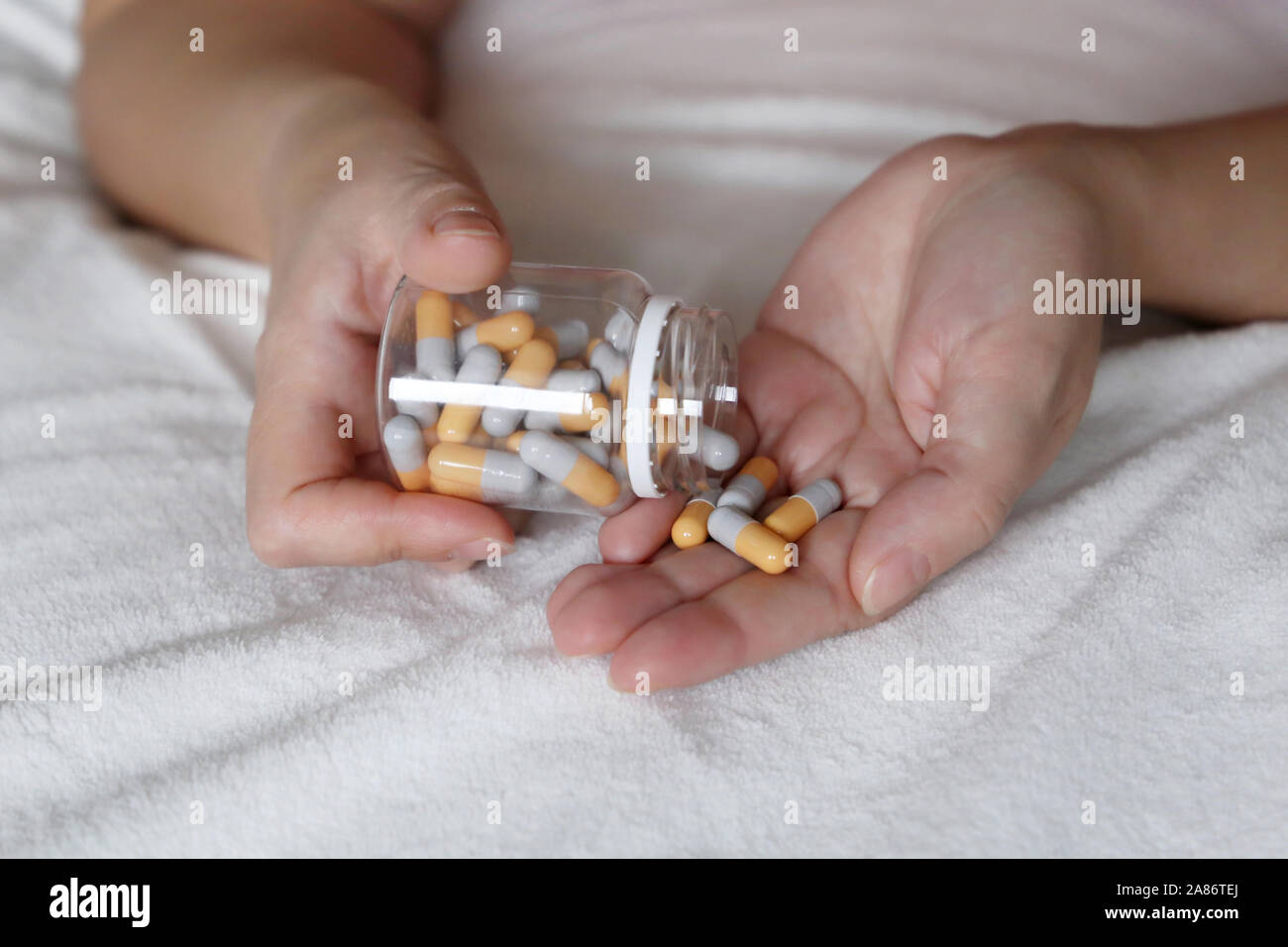 Frau mit Pillen, weibliche Hände auf dem Bett mit Tabletten und Kapseln. Konzept der Vitamine für die Schönheit, Diet Pill, Empfängnisverhütung, Behandlung, Abtreibung Stockfoto