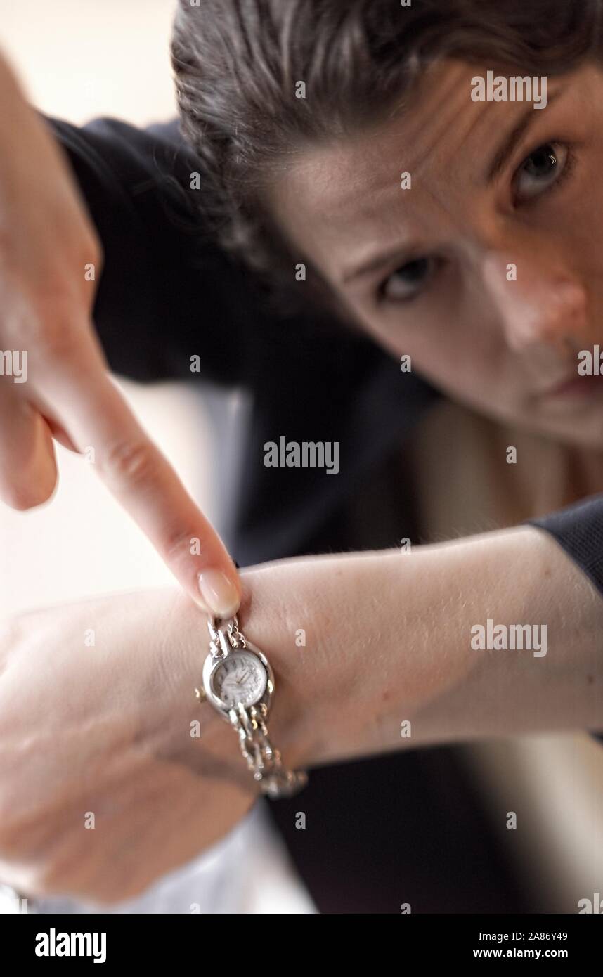 Kaukasische Frau darauf hin, die Zeit auf ihre Armbanduhr Stockfoto