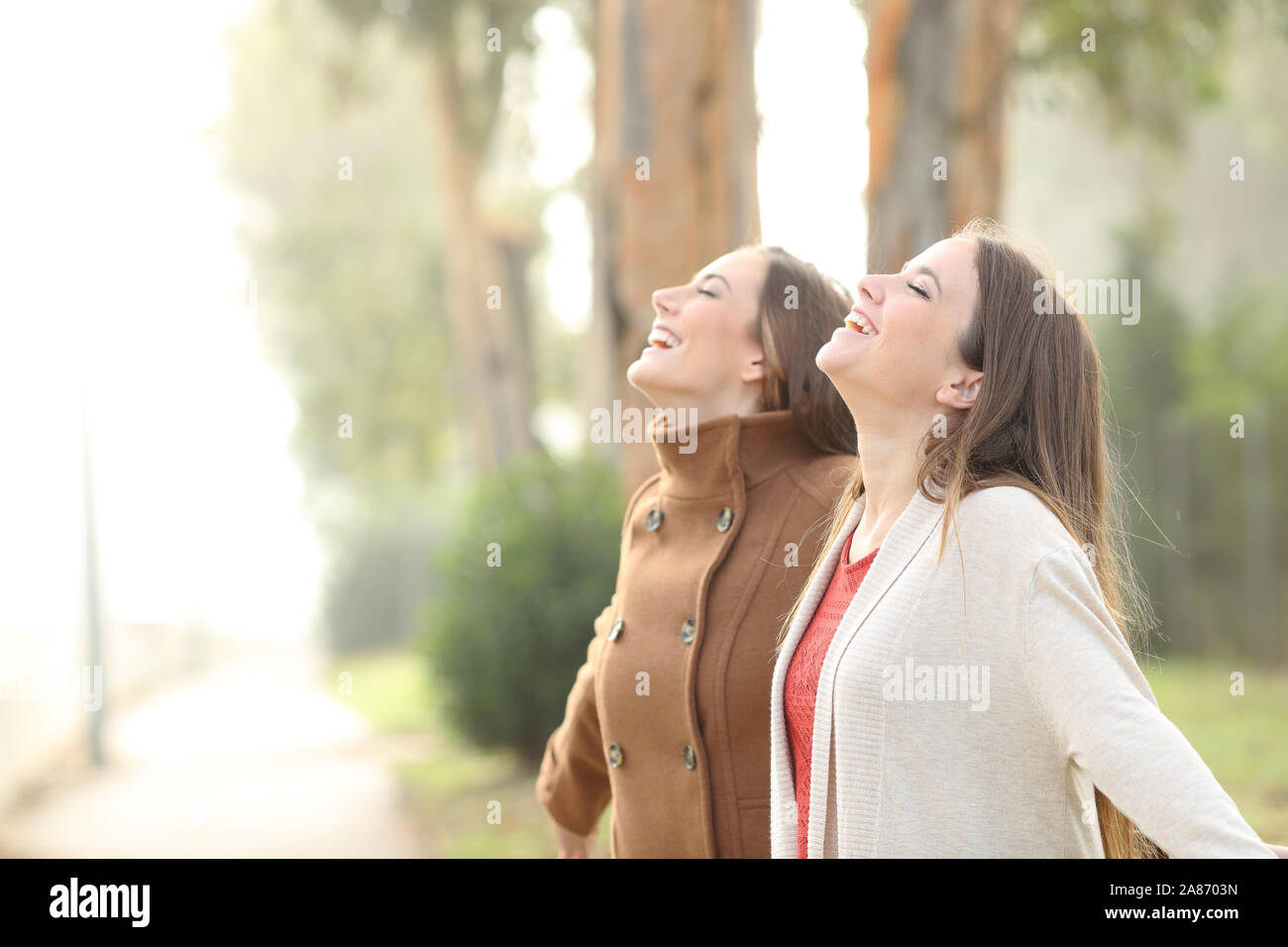Zwei glückliche Frauen tief atmen frische Luft stehend in einem Park Stockfoto