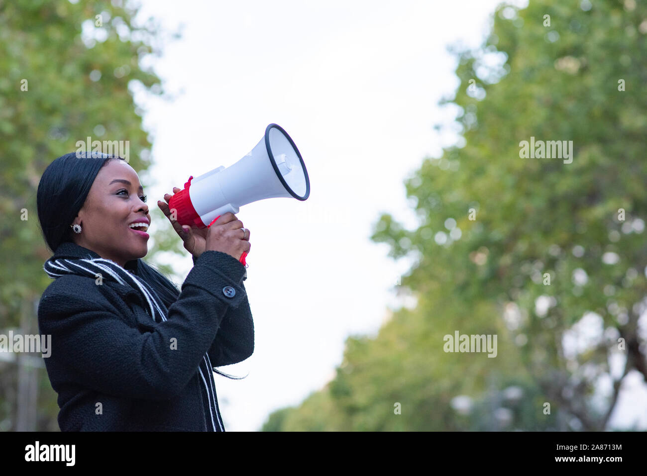 Mujer afroamericana se Comunica gritando Fuerte sosteniendo un Megáfono, expresando éxito y concepto Positivo, Idee para Marketing o Ventas. Stockfoto