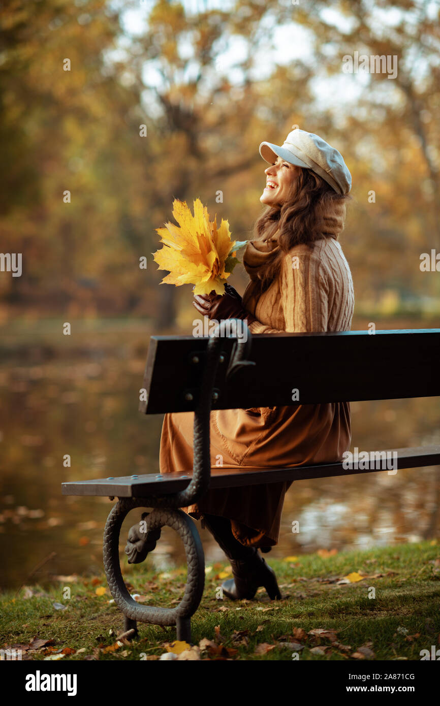 Hallo Herbst. Volle Länge Happy Elegant 40 Jahre alte Frau in die jacke, rock, hut, handschuhe und Schal mit gelben Blätter, während s bei copy Space Stockfoto