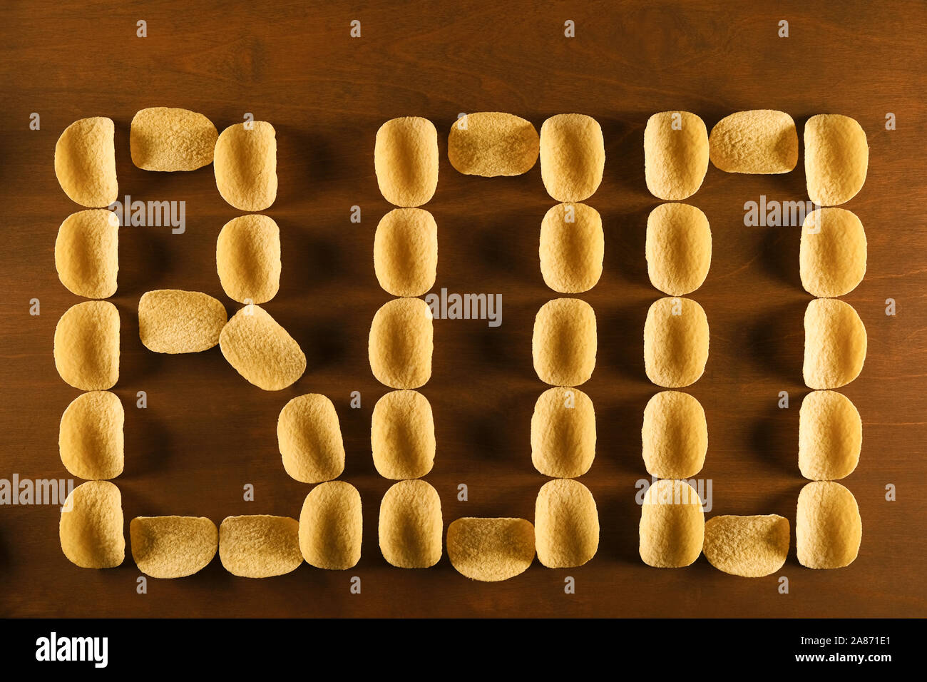 Kartoffelchips auf einem braunen Holztisch, Hintergrund mit Boo Inschrift, Thema der Fast Food, ungesunde Ernährung, erhöhtes Risiko für Fettleibigkeit, unheimlichen Hintergrund Stockfoto