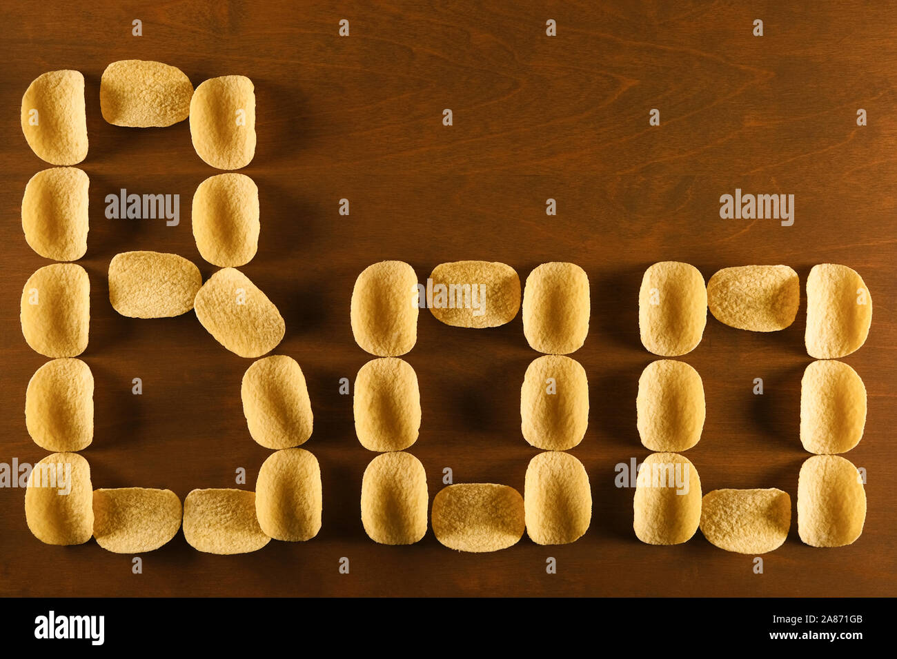 Gelbe Chips auf einem braunen Holztisch, Hintergrund mit der Aufschrift buh, scary Thema fast food, ungesunde Ernährung, erhöhtes Risiko für Fettleibigkeit Stockfoto