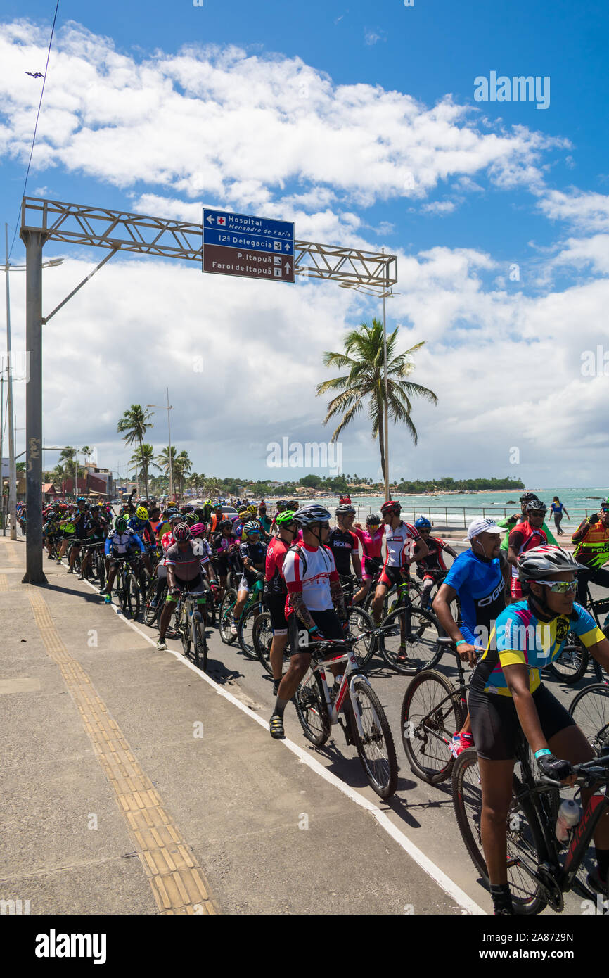 Gruppe der Radfahrer auf den Straßen von itapua Nachbarschaft auf der Welt Autofreier Tag - Strand im Hintergrund Stockfoto