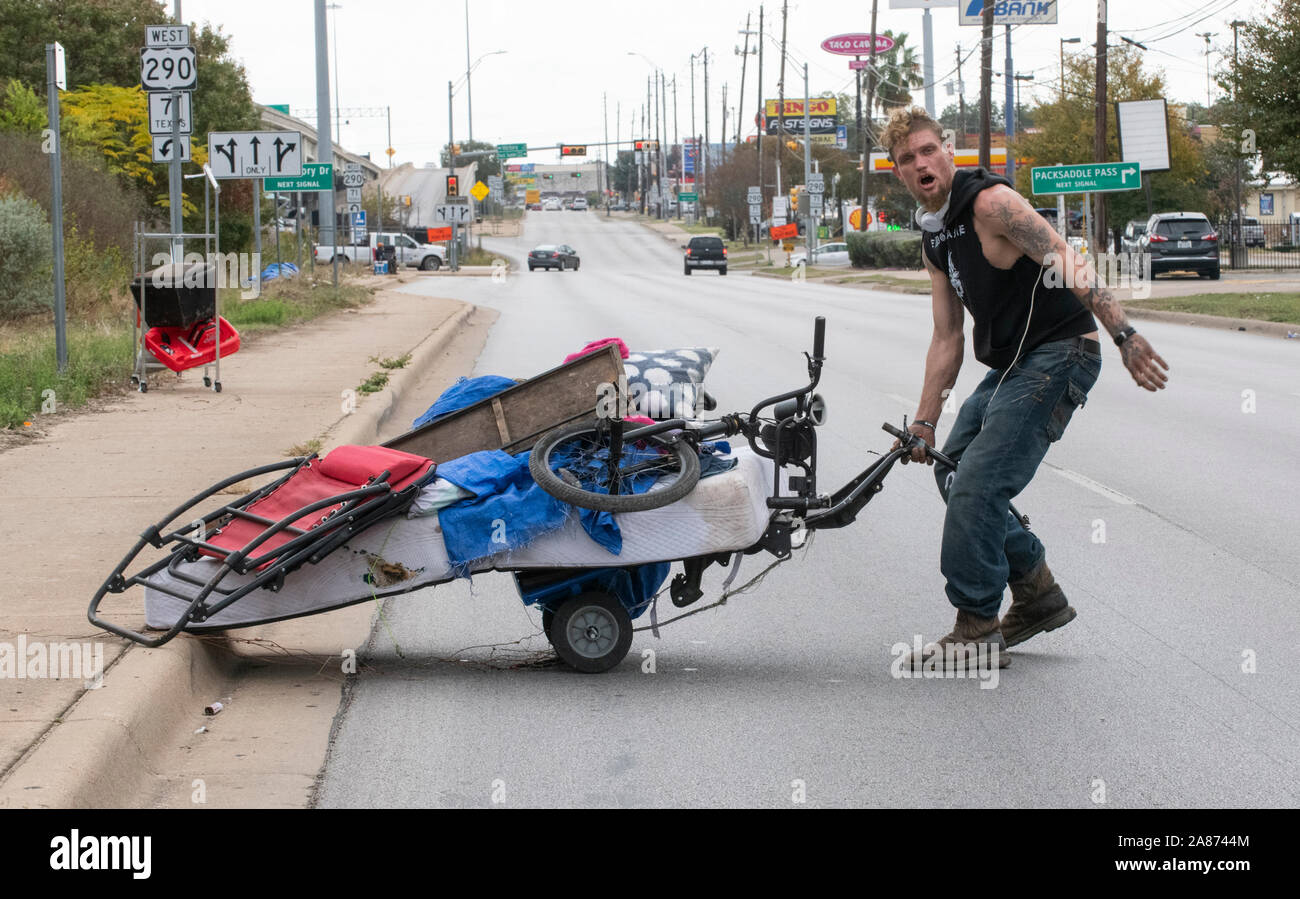 Austin, Texas, USA, Nov. 6, 2019: Ray Harvey bewegt seine beloingings über die Straße am dritten Tag eines staatlich sanktionierten Obdachlose camping Durchgreifen in Texas' Hauptstadt. Auf Bestellungen von Texas reg. Greg Abbott, Autobahn Besatzungen sind Clearing 17 Obdachlose lagern auf Autobahnen identifiziert. Stockfoto