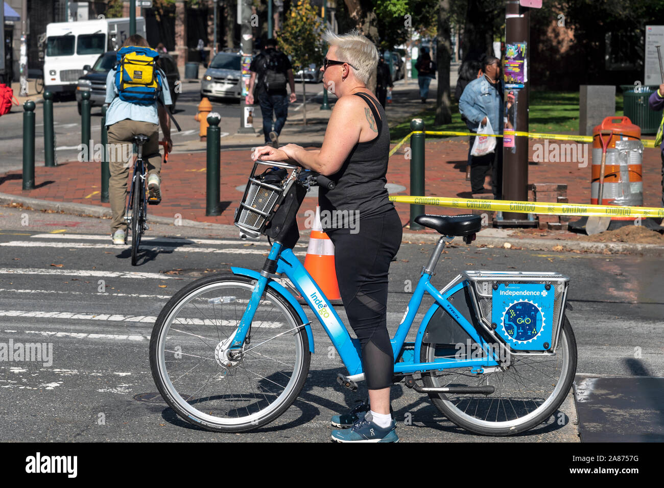 Frau mittleren Alters steht mit dem Fahrrad an der Kreuzung, Philadelphia, Pennsylvania, USA Stockfoto