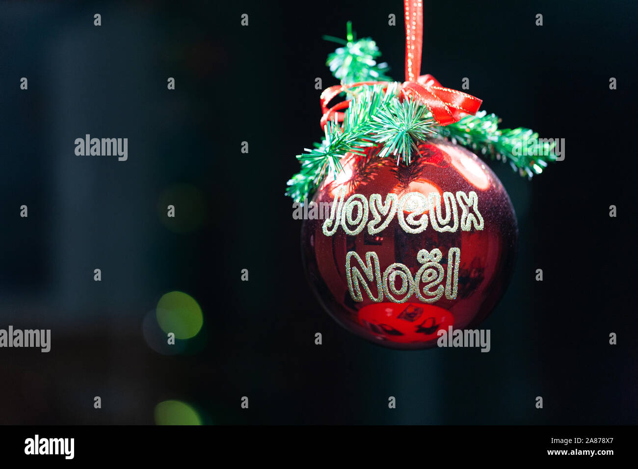 Frohe Weihnachten in französischer Sprache auf einem Red christmas Ball auf schwarzem Hintergrund Stockfoto