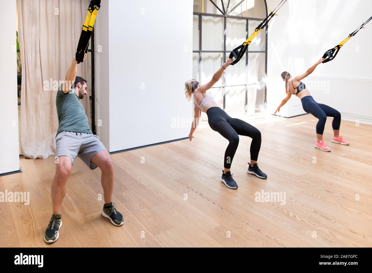 Drei Personen, die die Arbeit tun, Trx power zieht in ein Fitnessstudio mit gefederten Bügel und ihre Oberkörper drehen Stockfoto
