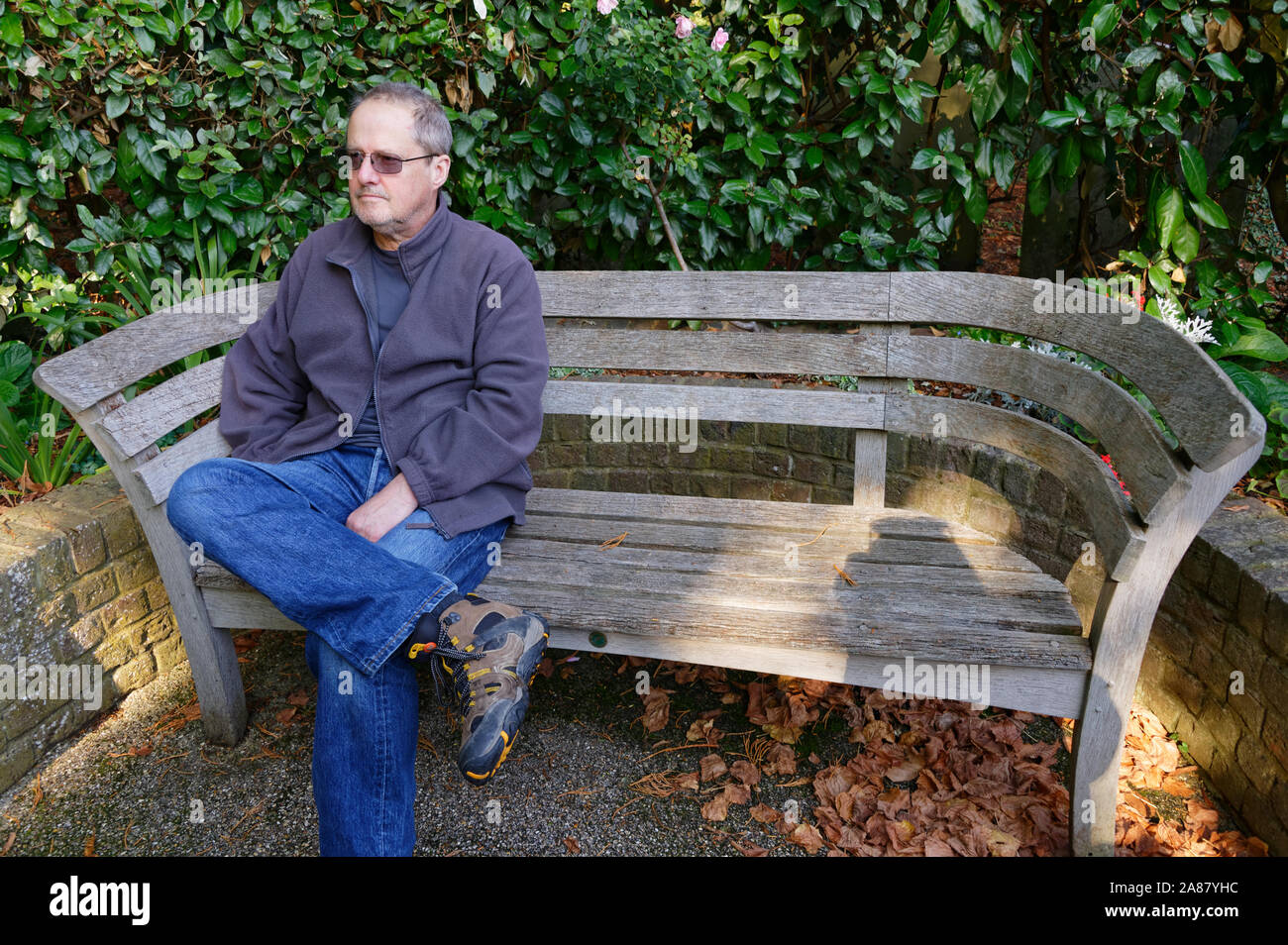 Ein Mann sitzt auf einem hölzernen Sitz Stockfoto