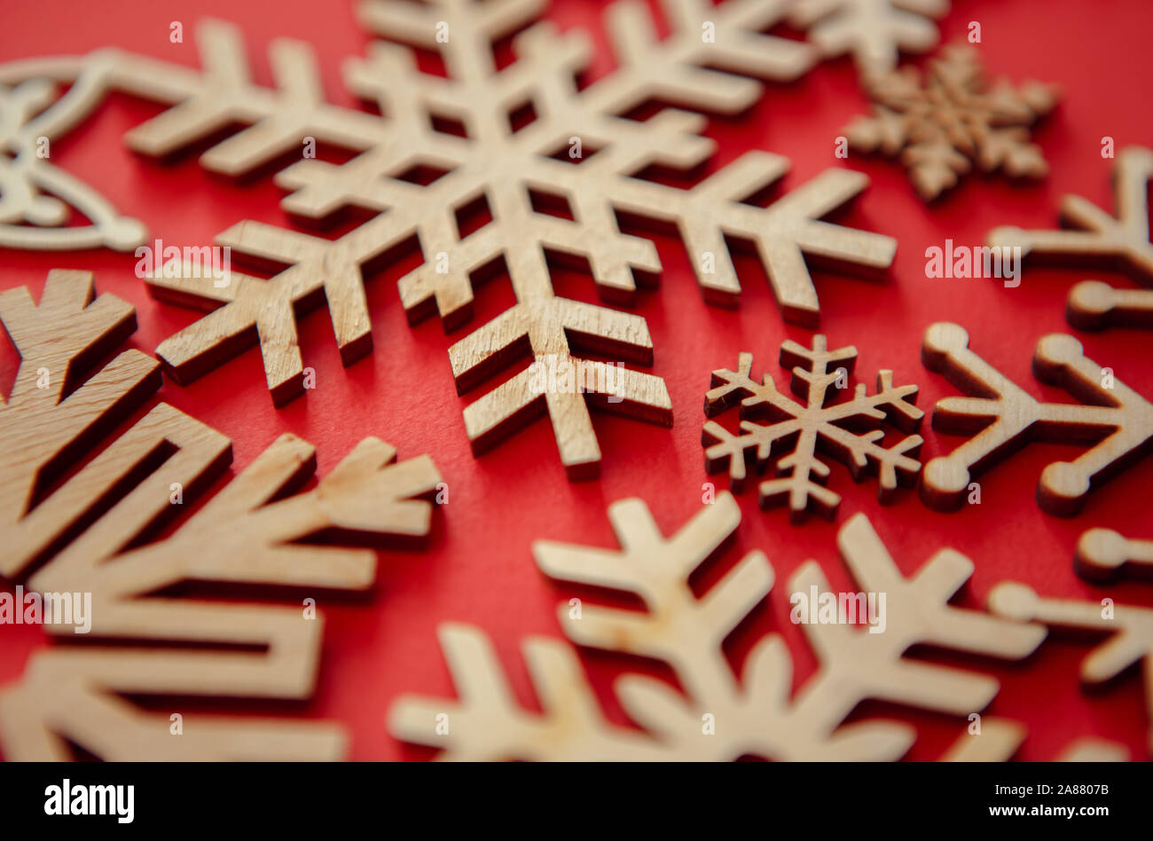 Handgefertigten Holzmöbeln Schneeflocken auf rotem Hintergrund. Weihnachten und ein glückliches Neues Jahr handgefertigte Dekorationen in Nahaufnahme. winter Urlaub Feiern und Deco Stockfoto