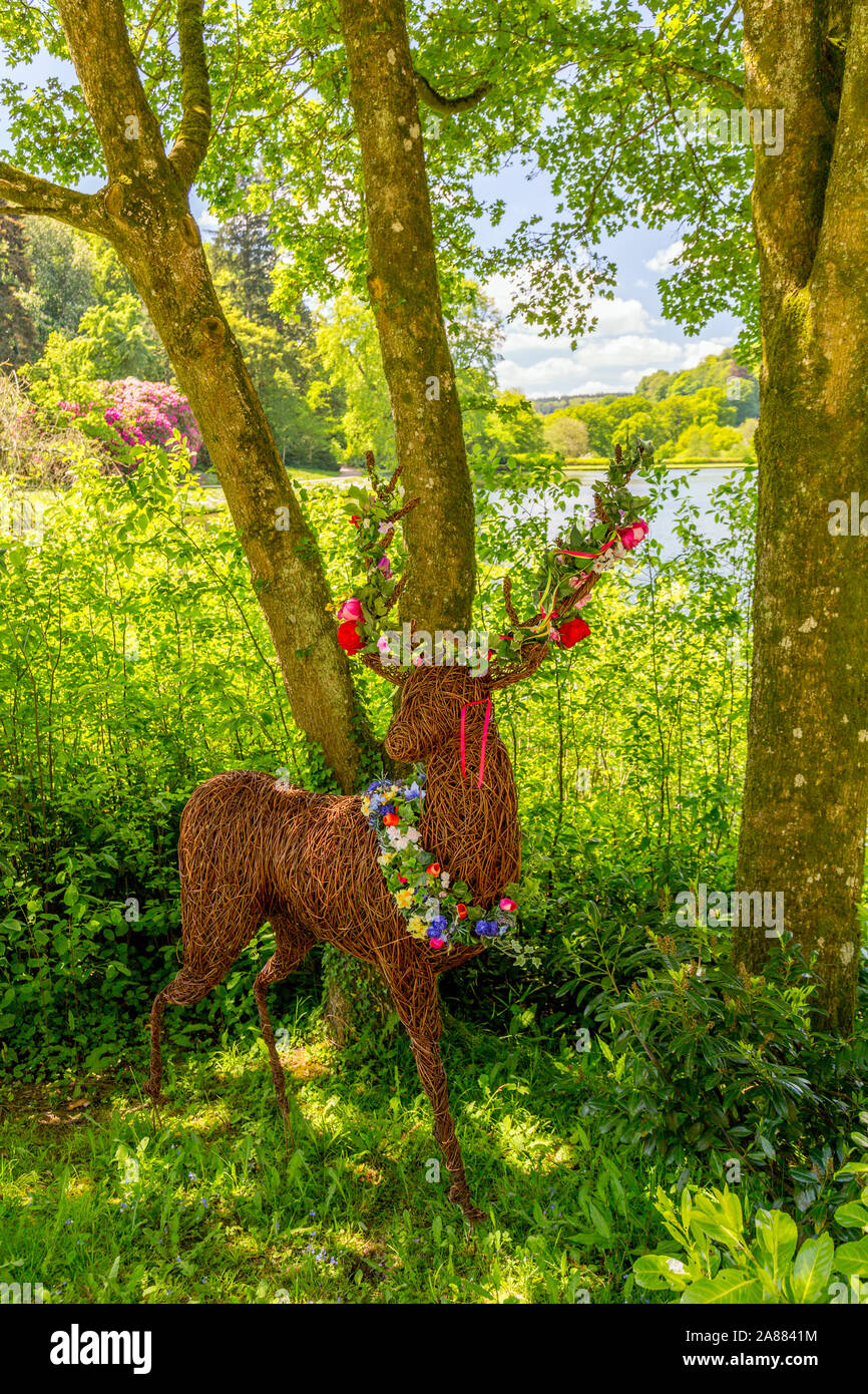 Ein willow Rotwild Skulptur mit Blumenschmuck am See bei Stourhead Gardens, Wiltshire, England, Großbritannien Stockfoto