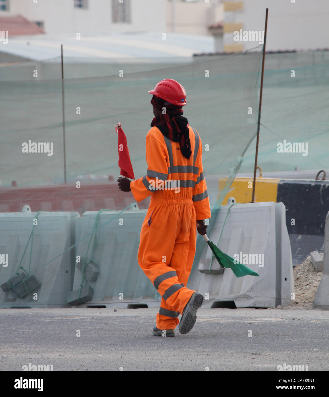 Expat Arbeiter Hilfe Schwere Fahrzeug auf der Straße mit einer roten und grünen Flagge in Katar Stockfoto
