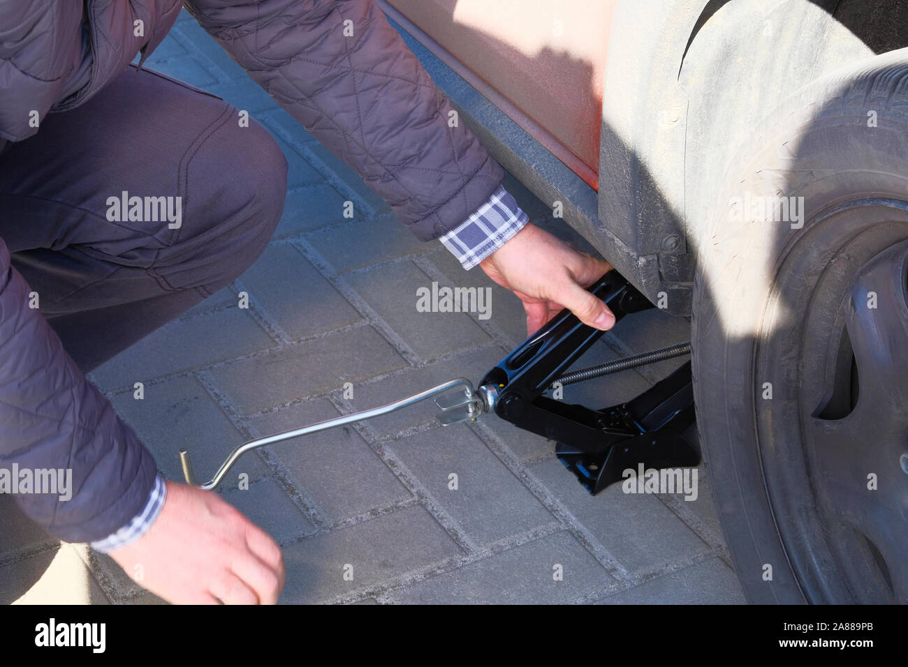 Hydraulische Wagenheber Auto für Rad wechseln zu heben. Mann nimmt Pkw Reifen zu ändern. Car Service. Ändern eines flachen Reifen auf der Straße. Stockfoto