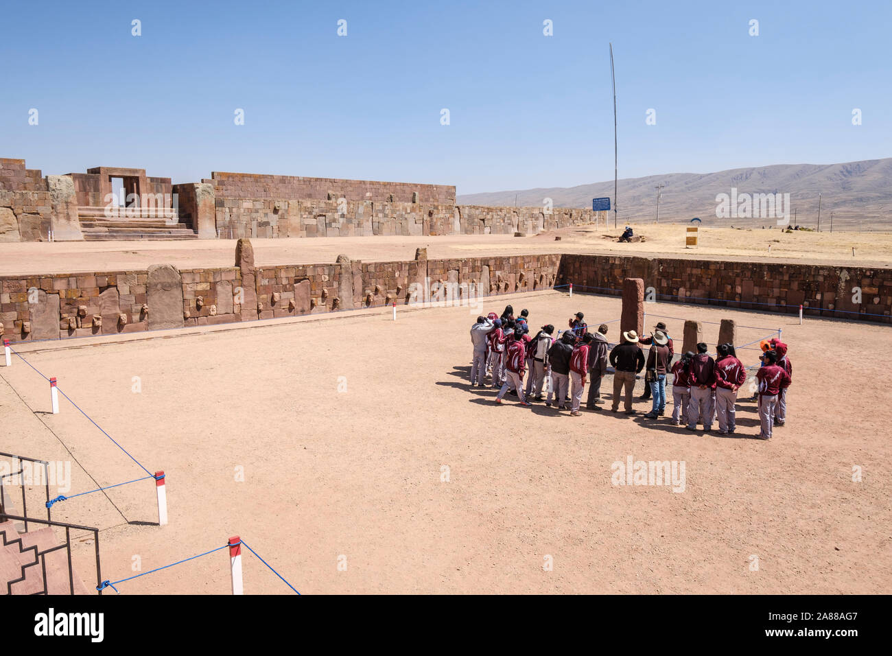 Bolivianischen Studierenden in Schuluniform beachten Sie die Anleitung auf halb-unterirdischen Tempel Eingang in Tiwanaku archäologischen Komplex, Bolivien Stockfoto