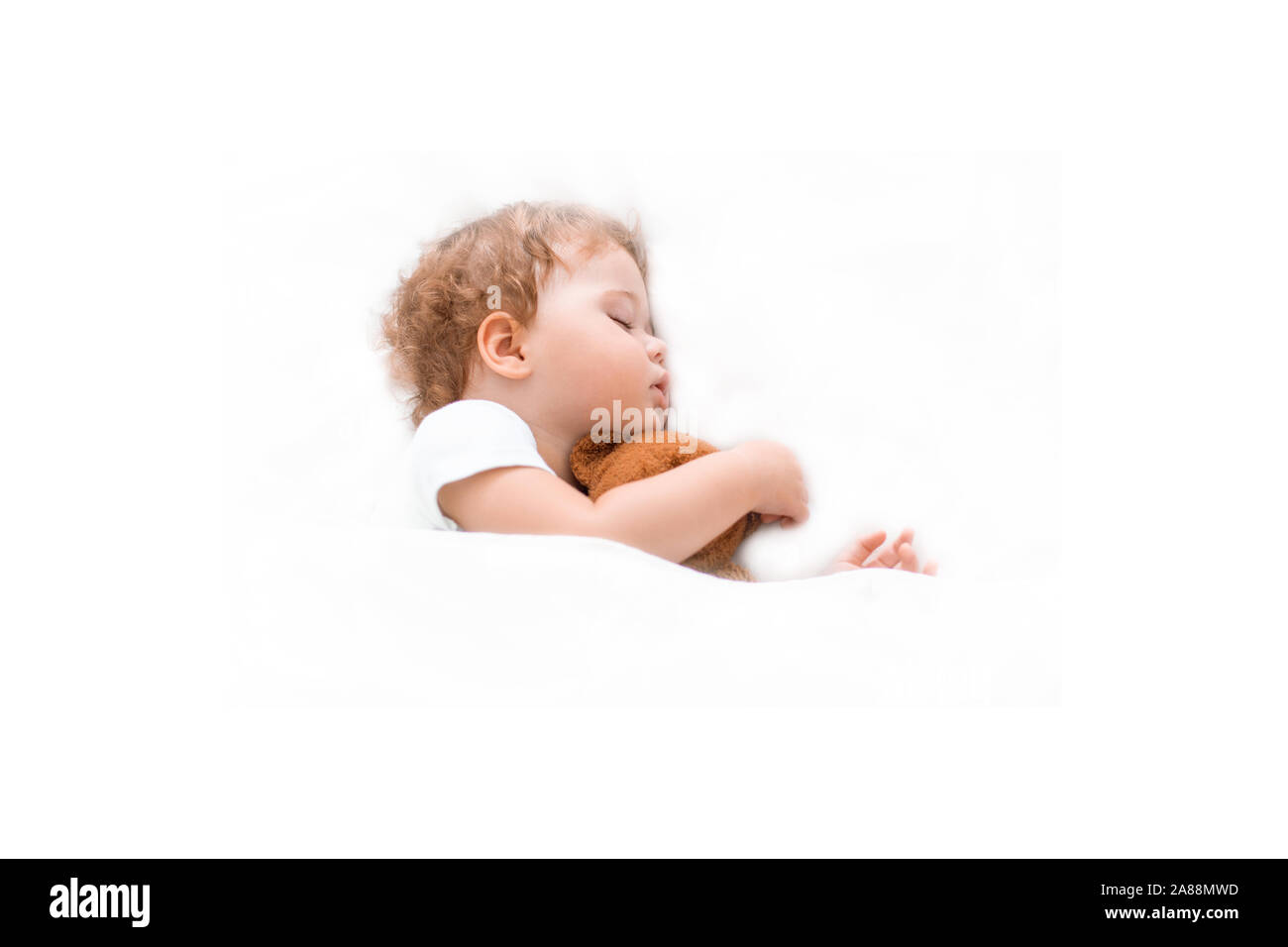 Baby Kind schläft auf einer sauberen Bettdecke umarmt einen Teddybären. Kaukasier Kind Mädchen Junge sitzt Träume auf ein großes Bett, weißen Hintergrund. Lockiges Haar, Cl Stockfoto