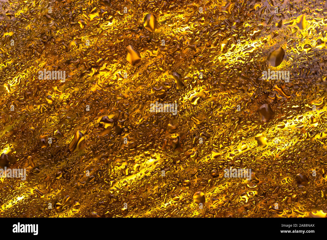 Glänzend goldenen kreativen Hintergrund mit Wassertropfen. Braunglas Textur mit Kondensat. Abstrakte leuchtend gelben Hintergrund. Festliche Karte, Rahmen. Stockfoto