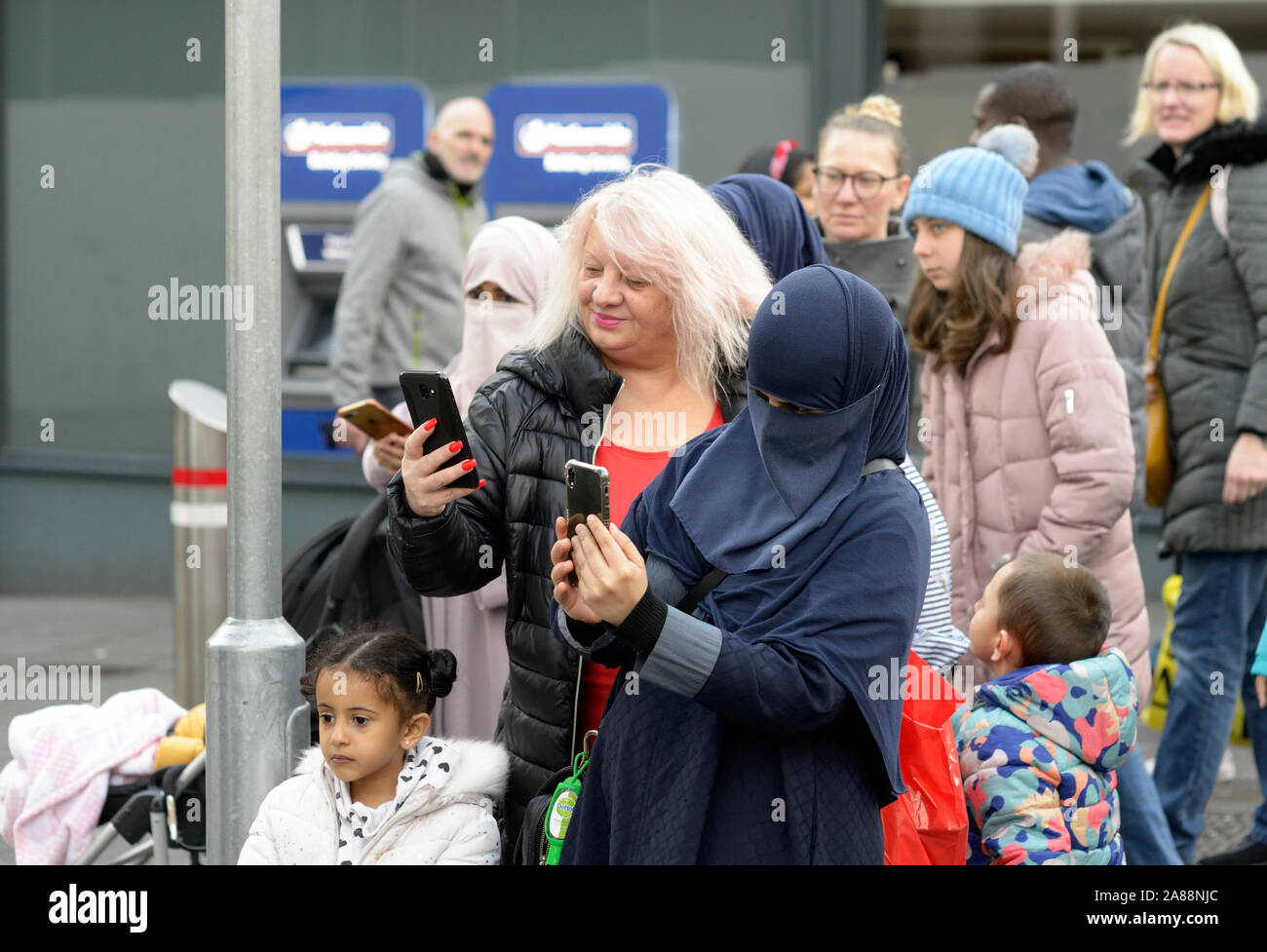 Verschiedene Leute beobachten ein puppenspieler. Ein Muslim in Niqab. Stockfoto