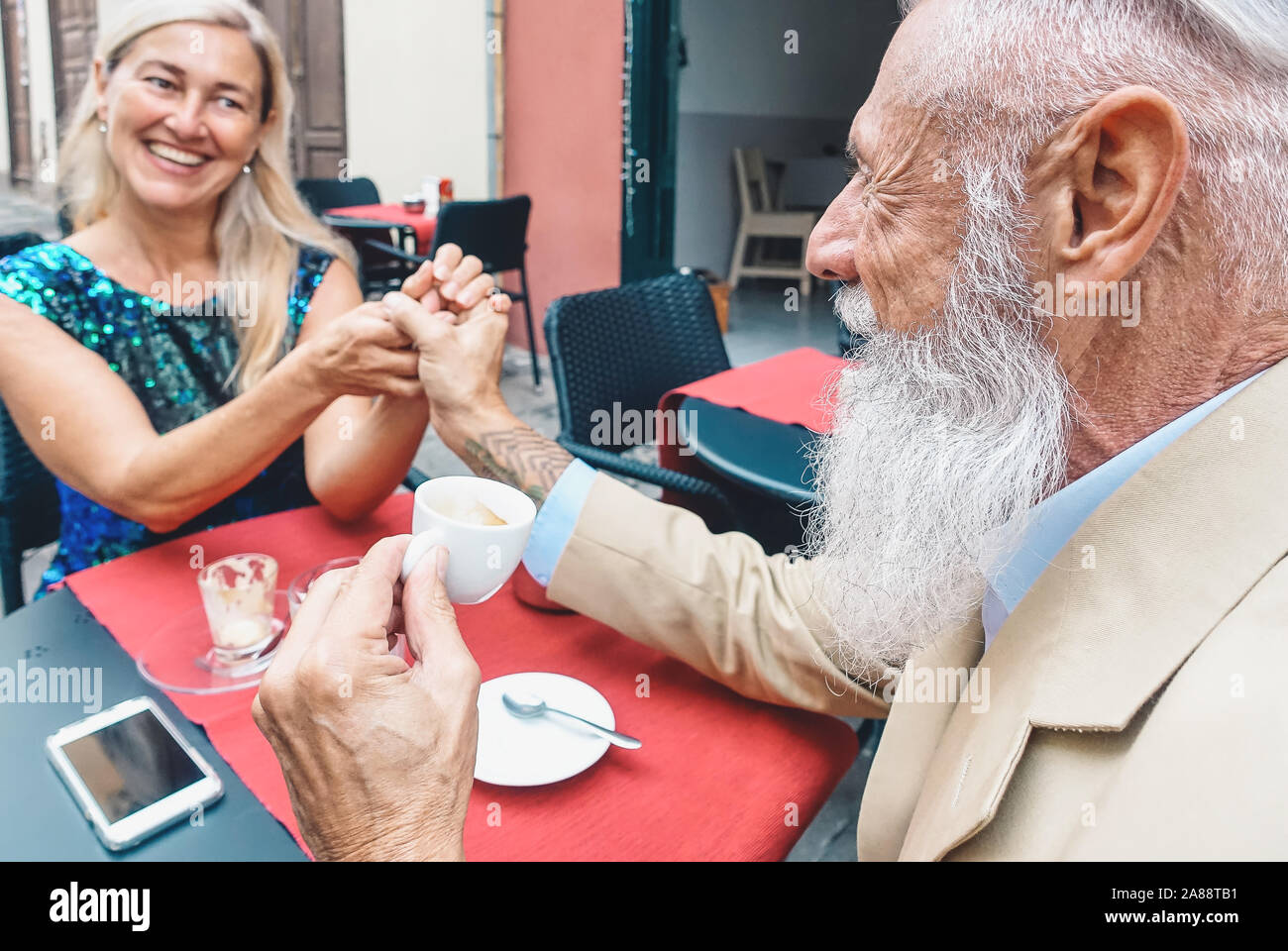 Gerne älteres Paar trinken Kaffee sitzen in einer Bar - Mode reifer Mann und Frau suchen einander, während Sie Pause in einem Restaurant Stockfoto