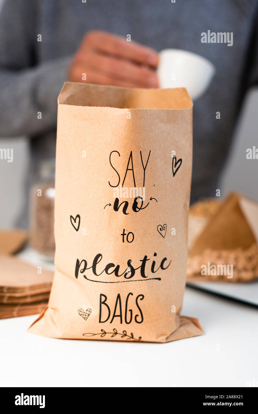 Ein kaukasischer Mann wiegen auf einer elektronischen Waage etwas trockene Kichererbsen auf braunem Papier Kegel, und eine Papiertüte in den Vordergrund mit dem Text sagen Nein zu pl Stockfoto