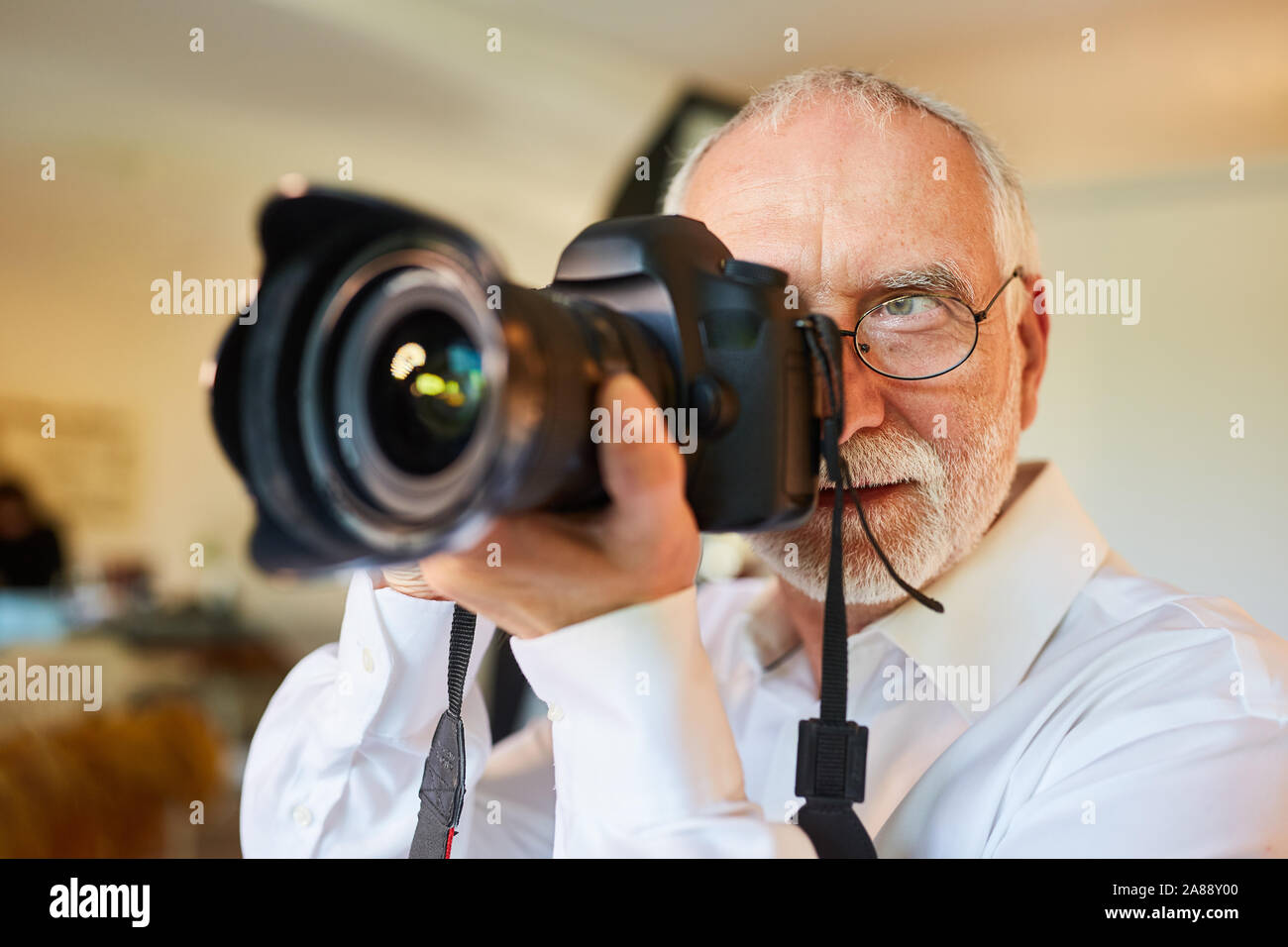 Senior als professioneller Fotograf mit der Kamera während dem Shooting Stockfoto