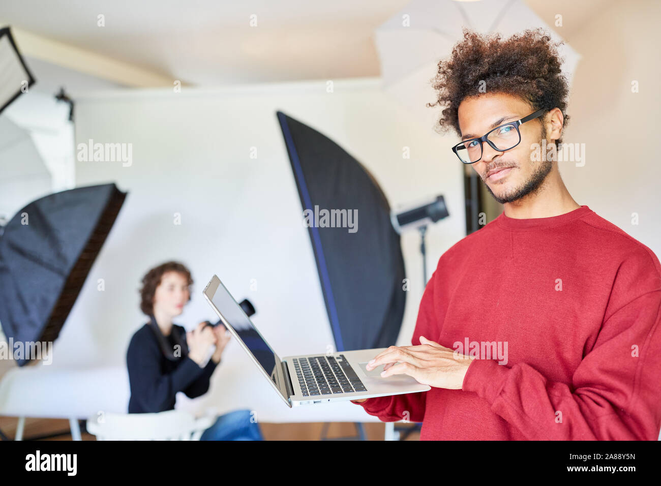Fotograf mit Laptop macht Backup beim Fotoshooting Stockfoto