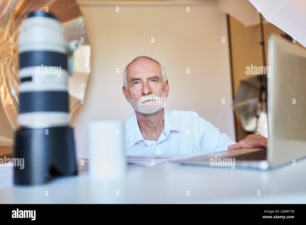 Senior Fotograf auf Laptop während der Datensicherung oder Bildbearbeitung Stockfoto