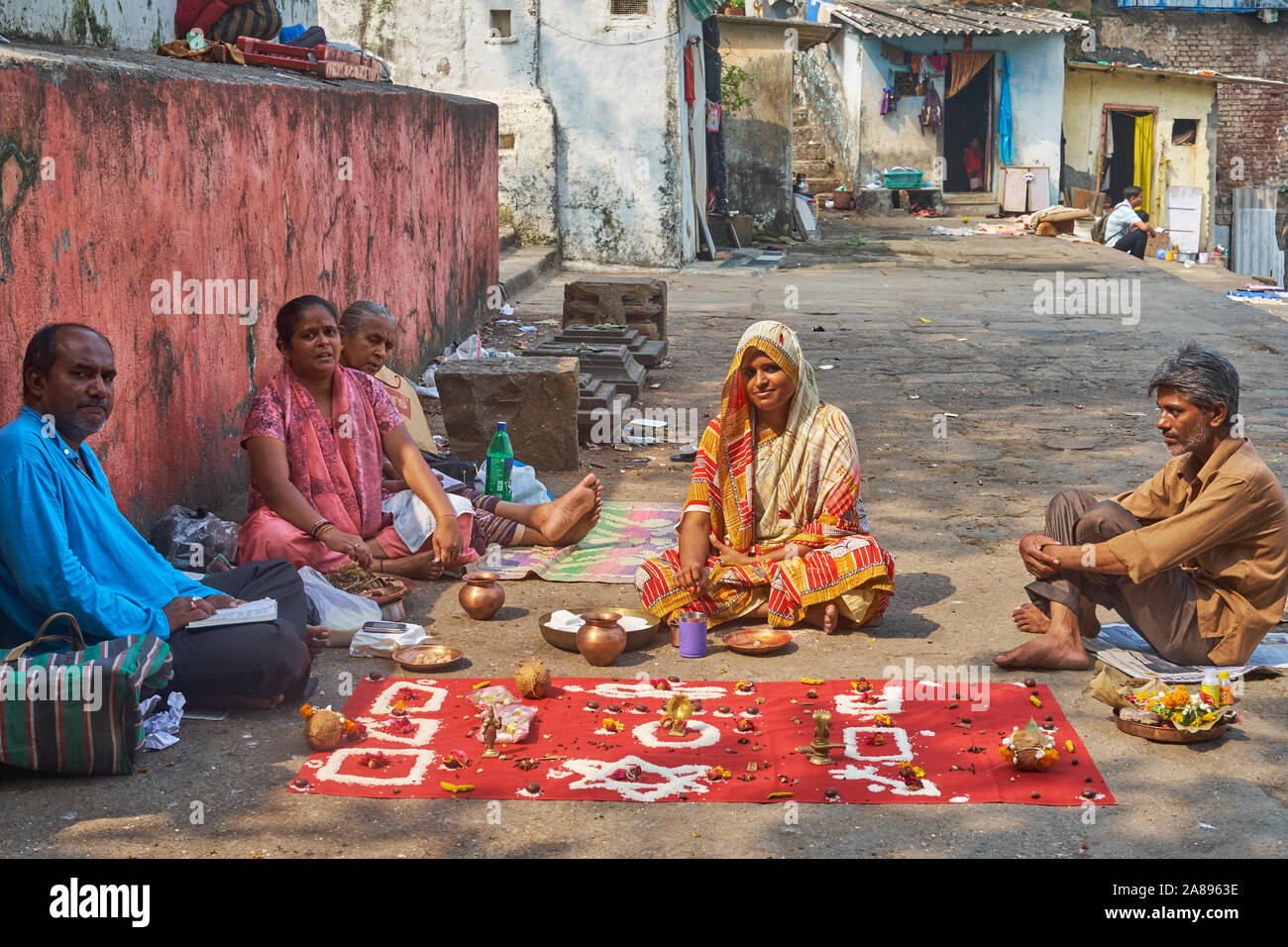 Eine hinduistische Familie von Heiligen Banganga Tank in Walkeshwar, Mumbai, Indien sitzen, die Durchführung einer Glück Ritual mit magischen Symbolen und Angebote Stockfoto