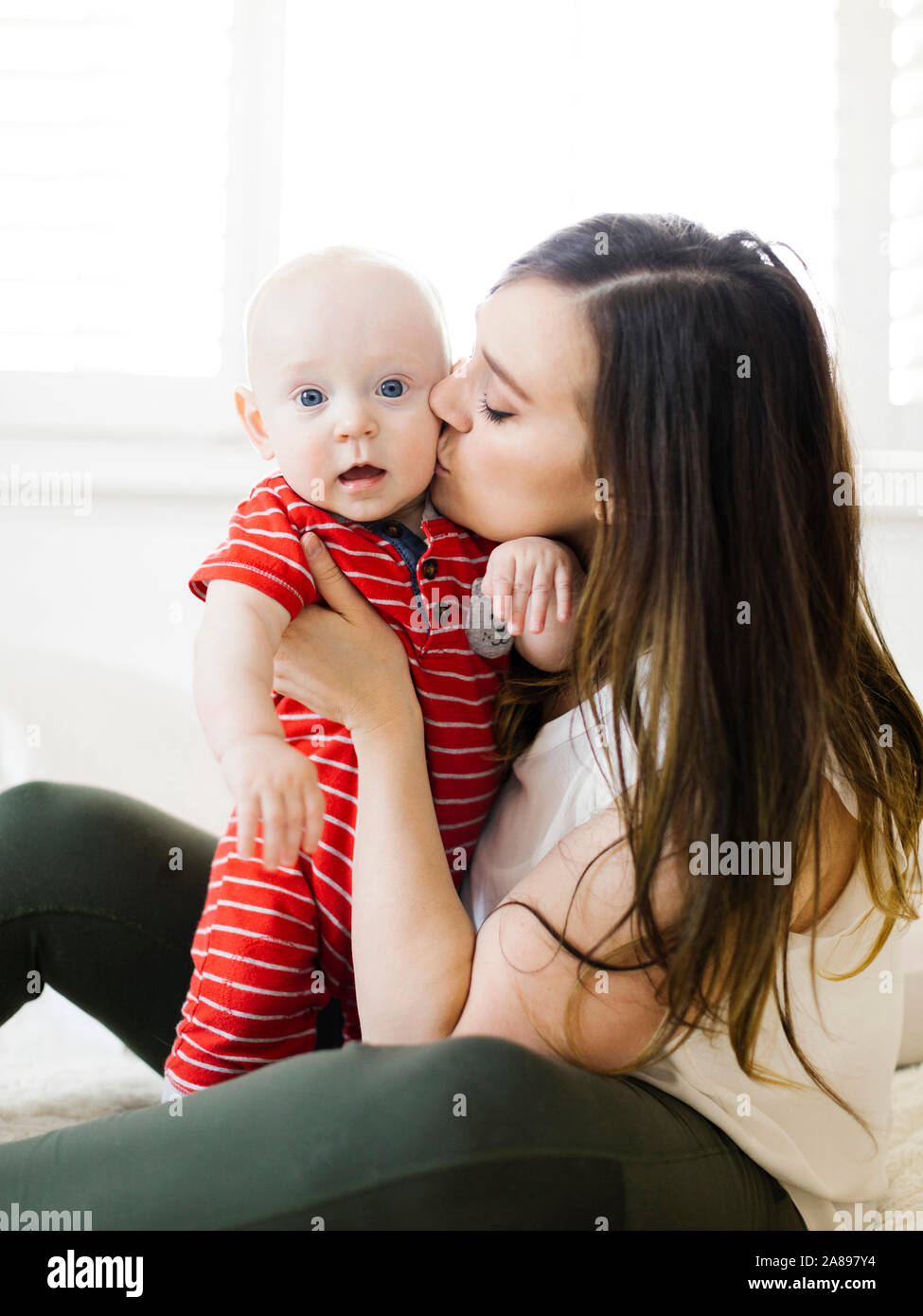 Frau küsst die Wange ihres kleinen Jungen Stockfoto