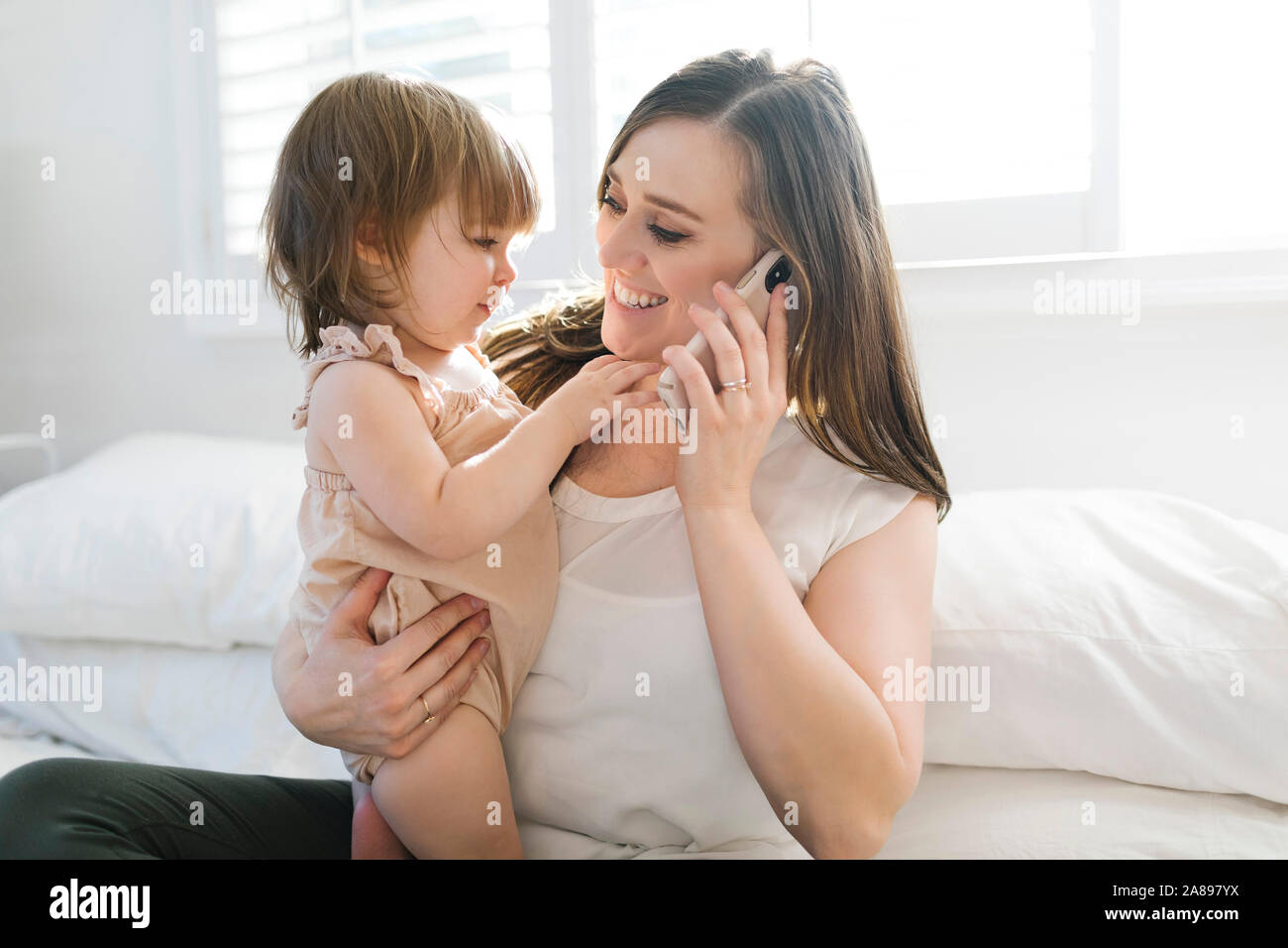 Frau hält Tochter während auf Telefonanruf Stockfoto