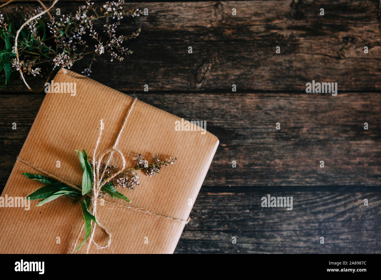 Geschenk verpackt in braunem Papier mit Schnur und Blumen Stockfoto