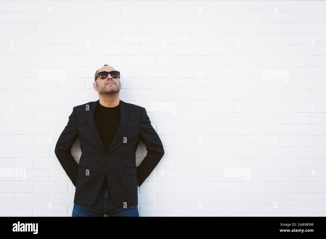 Mann mit Sonnenbrille und Blazer an der weißen Wand Stockfoto