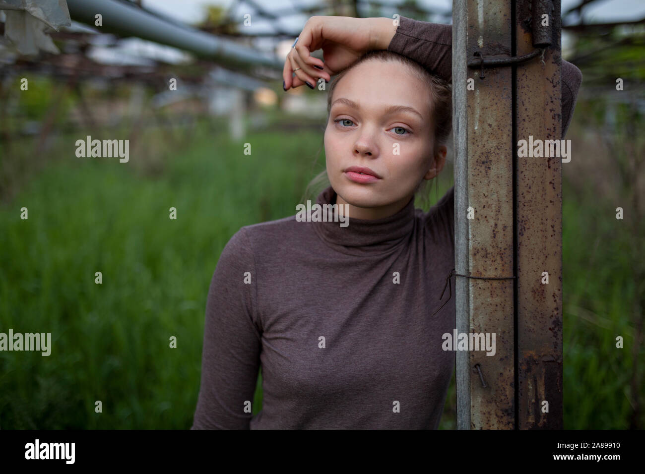 Junge Frau stützte sich auf hölzernen Pfosten Stockfoto