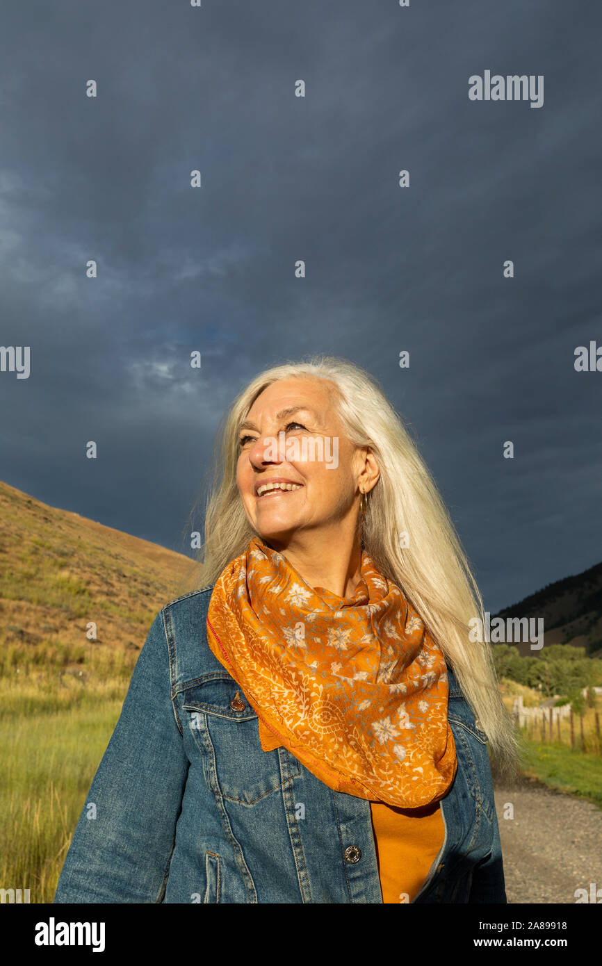 Lächelnd reife Frau trägt orange Schal im Feld Stockfoto