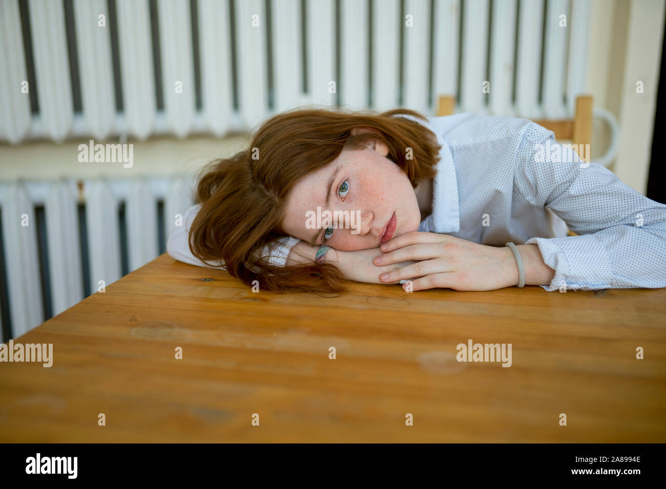 Junge Frau lehnte sich auf hölzernen Tisch Stockfoto