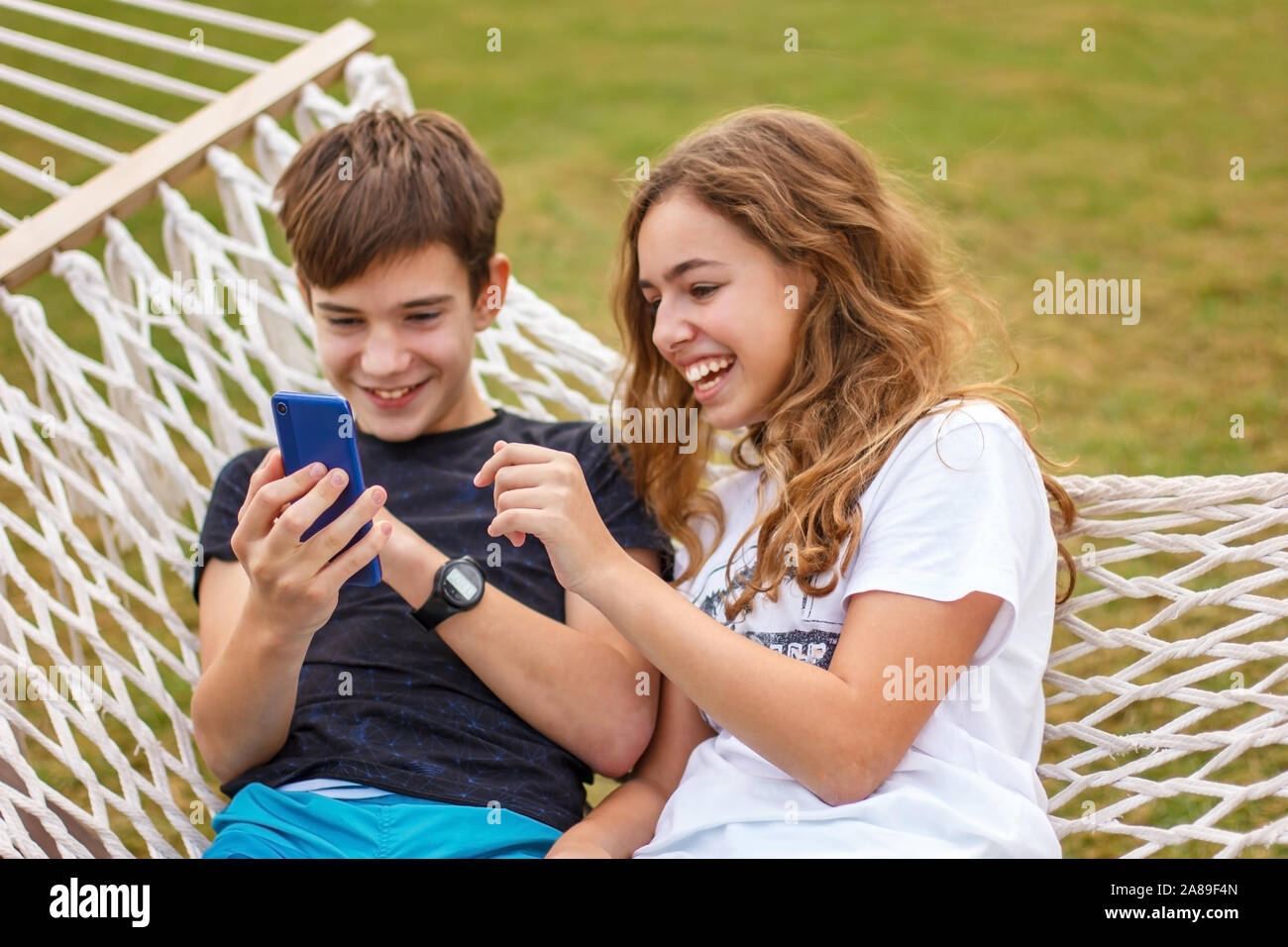 Paar junge glücklich Teens. Ein Mädchen und ein Kerl Lachen und ein Video auf einem Smartphone Stockfoto