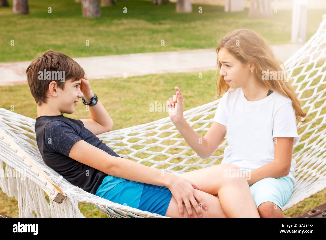 Paar junge glücklich Jugendliche. Mädchen und Jungen im Gespräch außerhalb des Chats an der Hängematte Stockfoto