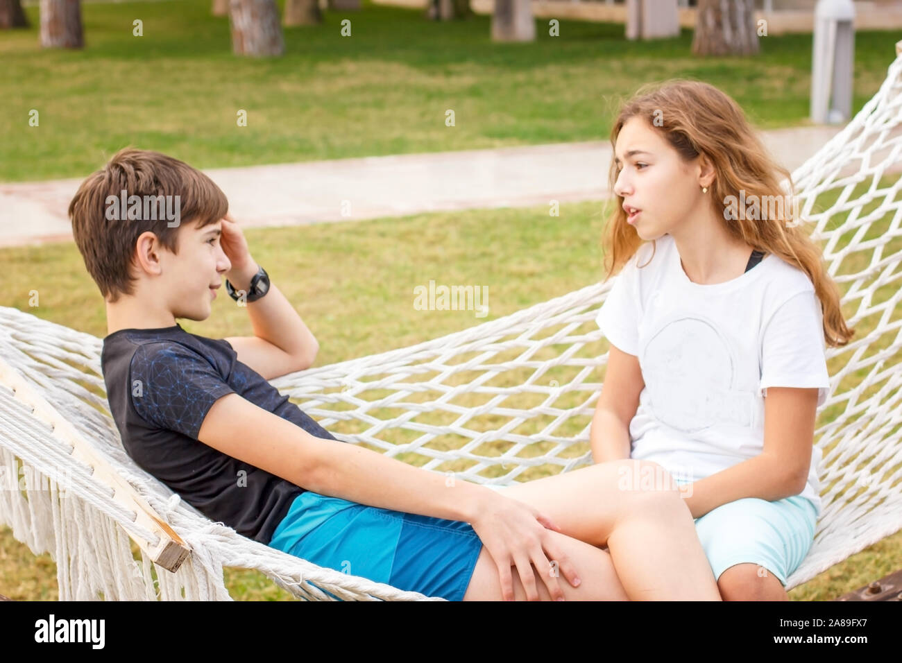 Paar junge glücklich Jugendliche. Mädchen und Jungen im Gespräch außerhalb des Chats an der Hängematte Stockfoto