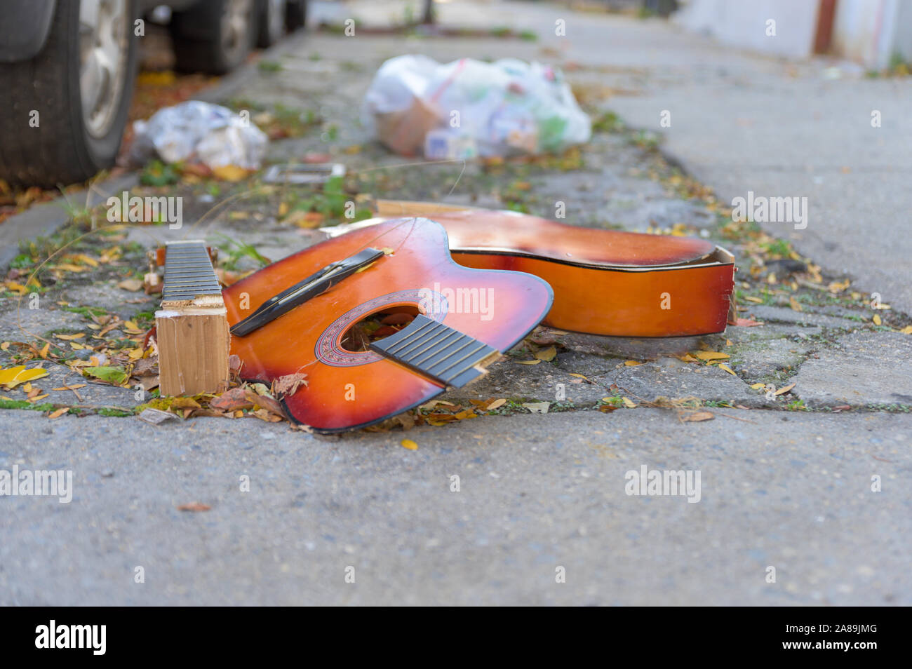 Eine kaputte alte Gitarre liegend auf dem Beton, auf einem New York City street verworfen Stockfoto