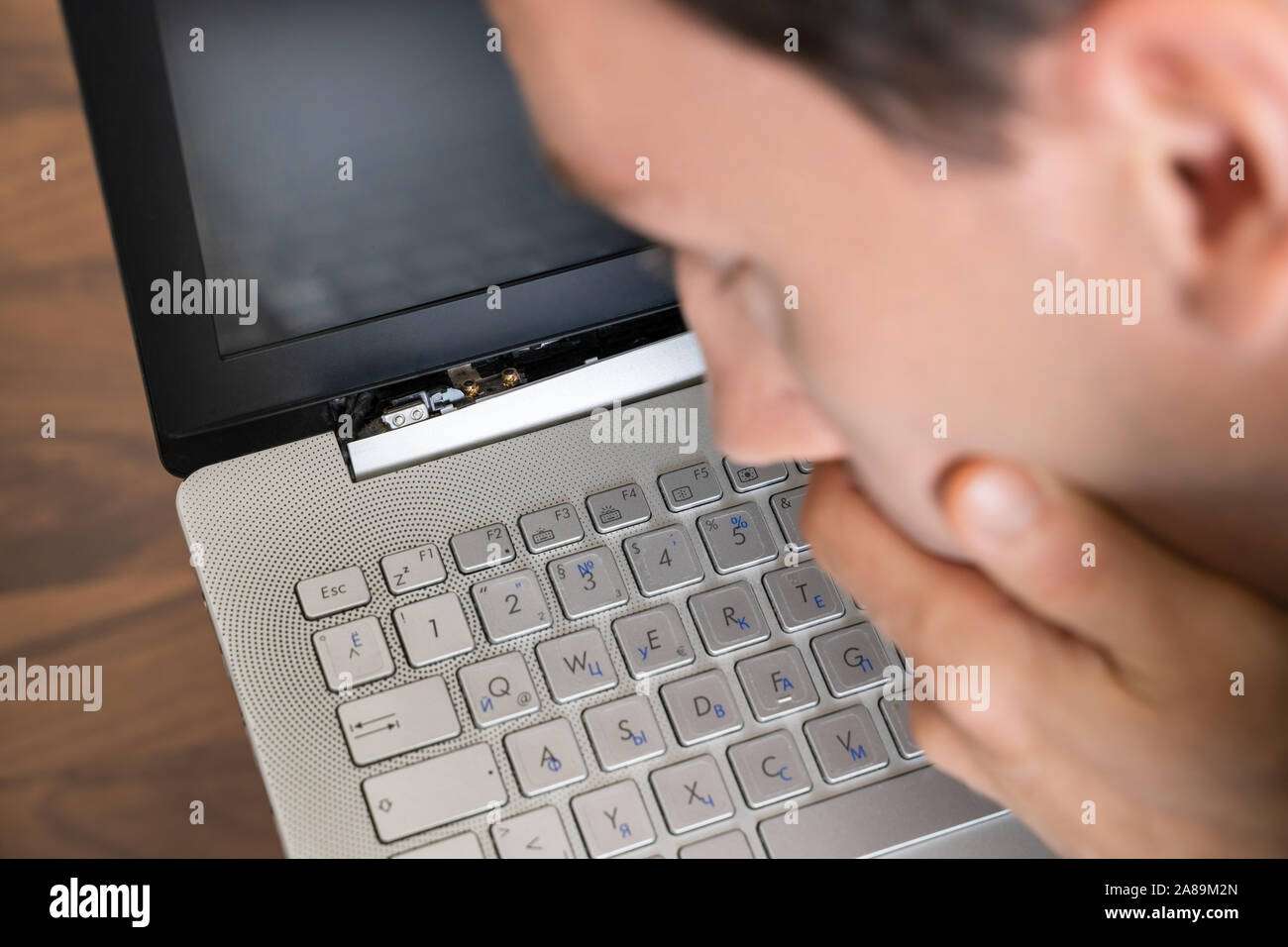 Mann an beschädigten Laptop mit defektem Bildschirm Attachment Suchen Stockfoto