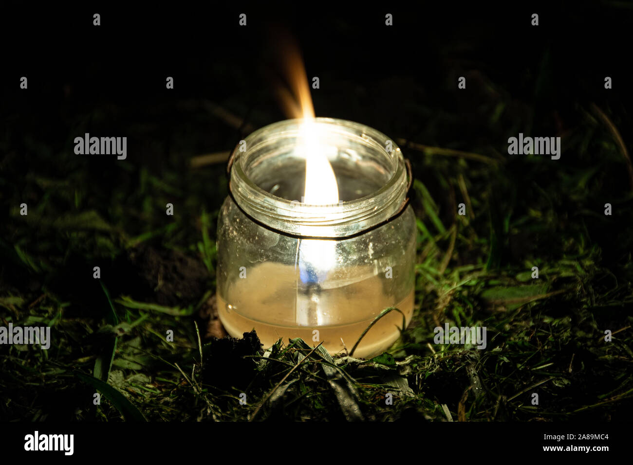 Kerze im Glas Glas im Gras. Nacht das Leben der Pflanzen im Garten Stockfoto
