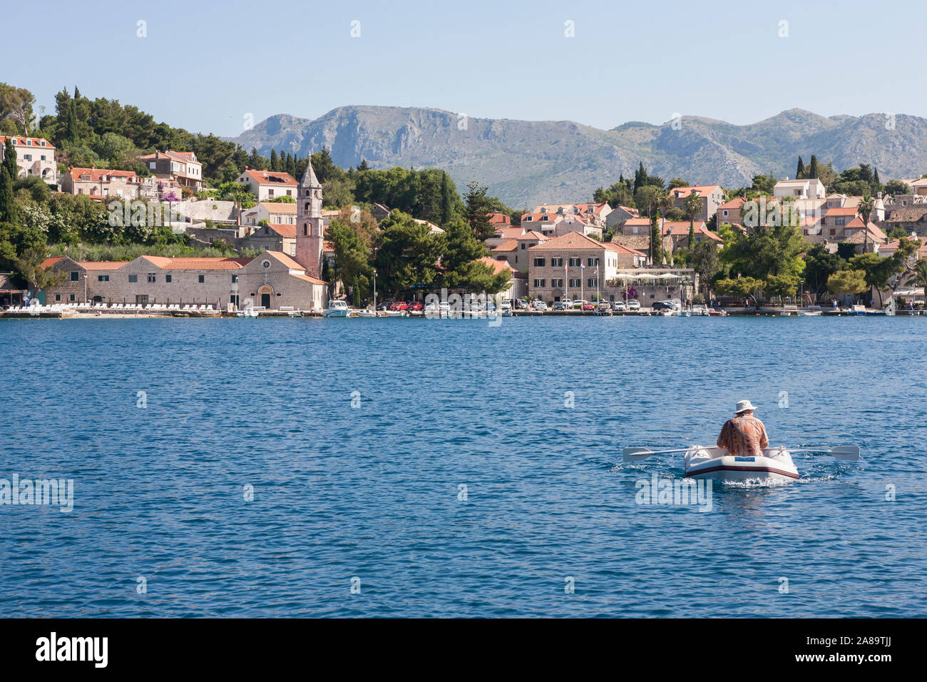 Morgen in Uvala Luka Cavtat (Cavtat Harbour), Dubrovnik-Neretva, Kroatien: Ein Mann reiht ein Schlauchboot über die Bucht. MODELL VERÖFFENTLICHT Stockfoto