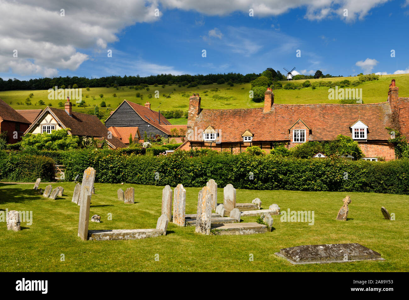 Aus rotem Backstein und Ziegeldach Cottages in Turville Dorf mit der hl. Jungfrau Maria Kirche, Friedhof und Cobstone Windmühle auf dem Hügel England Stockfoto