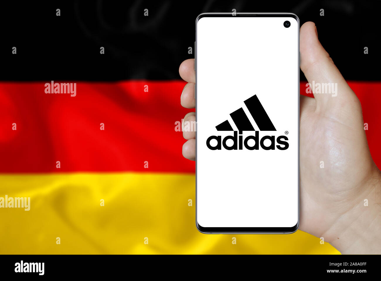 Logo der öffentlichen Unternehmen Adidas auf dem Smartphone angezeigt. Flagge Deutschland Hintergrund. Credit: PIXDUCE Stockfoto