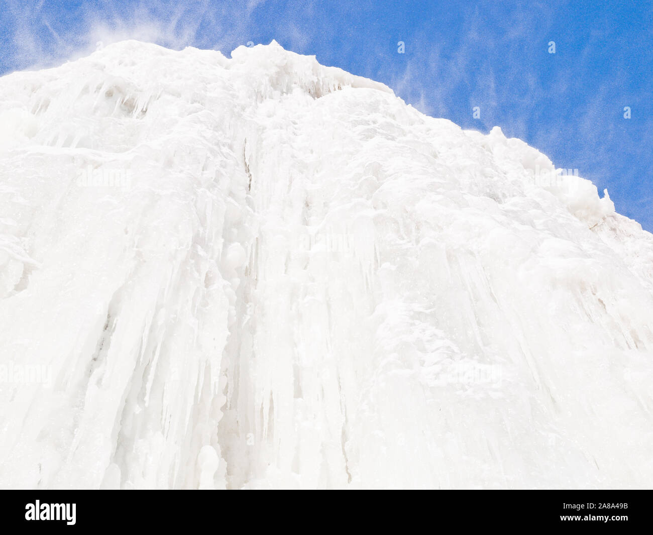 Eine dramatische Schiere hohe Wand von White Ice und Schneegestöber gegen einen klaren blauen Himmel Stockfoto