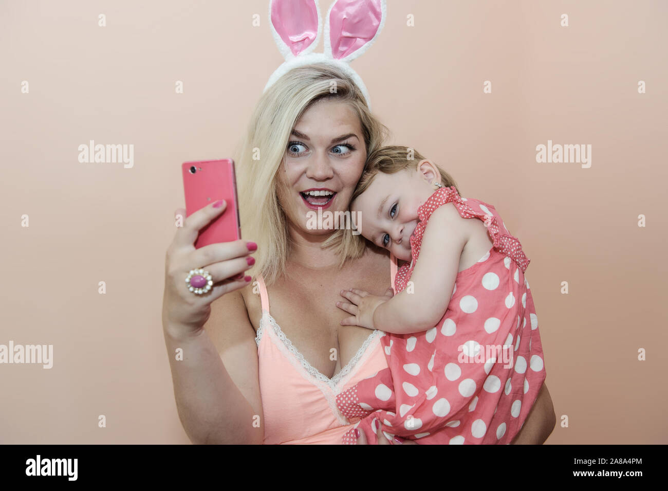 Mutter und Tochter machen selfie. Junge Mutter. Rosa Farbe Foto Stockfoto