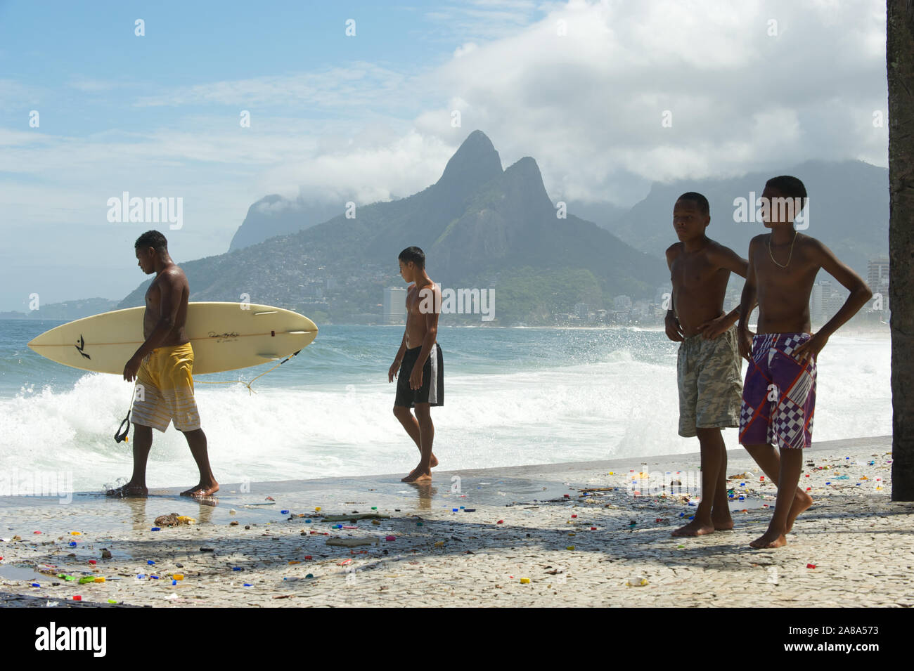 RIO DE JANEIRO - 16. MÄRZ 2011: Jungen Brasilianischen surfer Ipanema Spaziergänge auf der Promenade mit einem Surfbrett über Wellen in Arpoador. Stockfoto